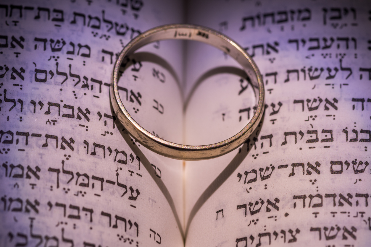 Life Cycle Events Close-up of the Hebrew Jewish bible with a wedding ring creating a heart shape shadow